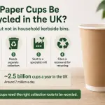 A stack of disposable paper coffee cups showing recyclability status in the UK